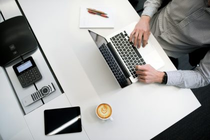 person using laptop on white wooden table; how to calculate markup