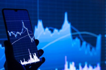 a person holding a cell phone in front of a stock chart; Leading Economic Index May 2026