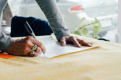 person writing on white plain paper on the table photography; e&o insurance