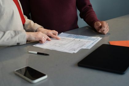 Two people reviewing documents at a table.; high deductible insurance plans