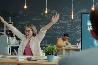 Woman celebrating success at her office desk.; workplace sound