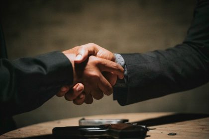 two people shaking hands over a wooden table; what is a non-compete agreement