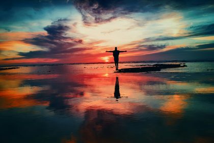 silhouette of person standing on rock surrounded by body of water; affordable life insurance
