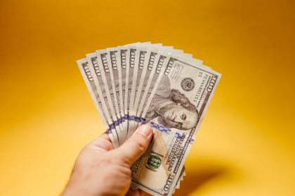 a hand holding a stack of twenty dollar bills; reasonable salary for an S corp