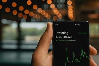 a person holding up a cell phone with a stock chart on it; sep ira vs roth ira