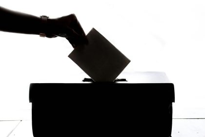 a person is casting a vote into a box; s corp election