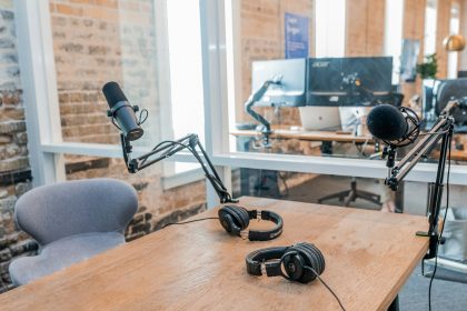 two black headphones on brown wooden table; podcast equipment for beginners