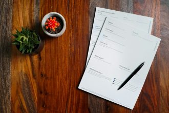 a wooden table topped with papers and a pen; what is a pro forma invoice