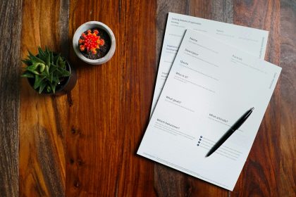 a wooden table topped with papers and a pen; what is a pro forma invoice