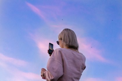 woman in sunglasses and pink top holding phone; discovery call