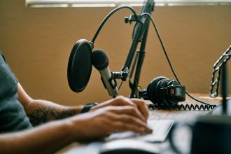 person holding microphone on microphone stand; how to start a podcast on spotify