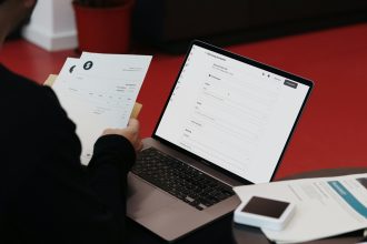 A person sitting at a desk with a laptop and papers; what is an invoice