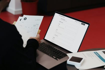A person sitting at a desk with a laptop and papers; what is an invoice