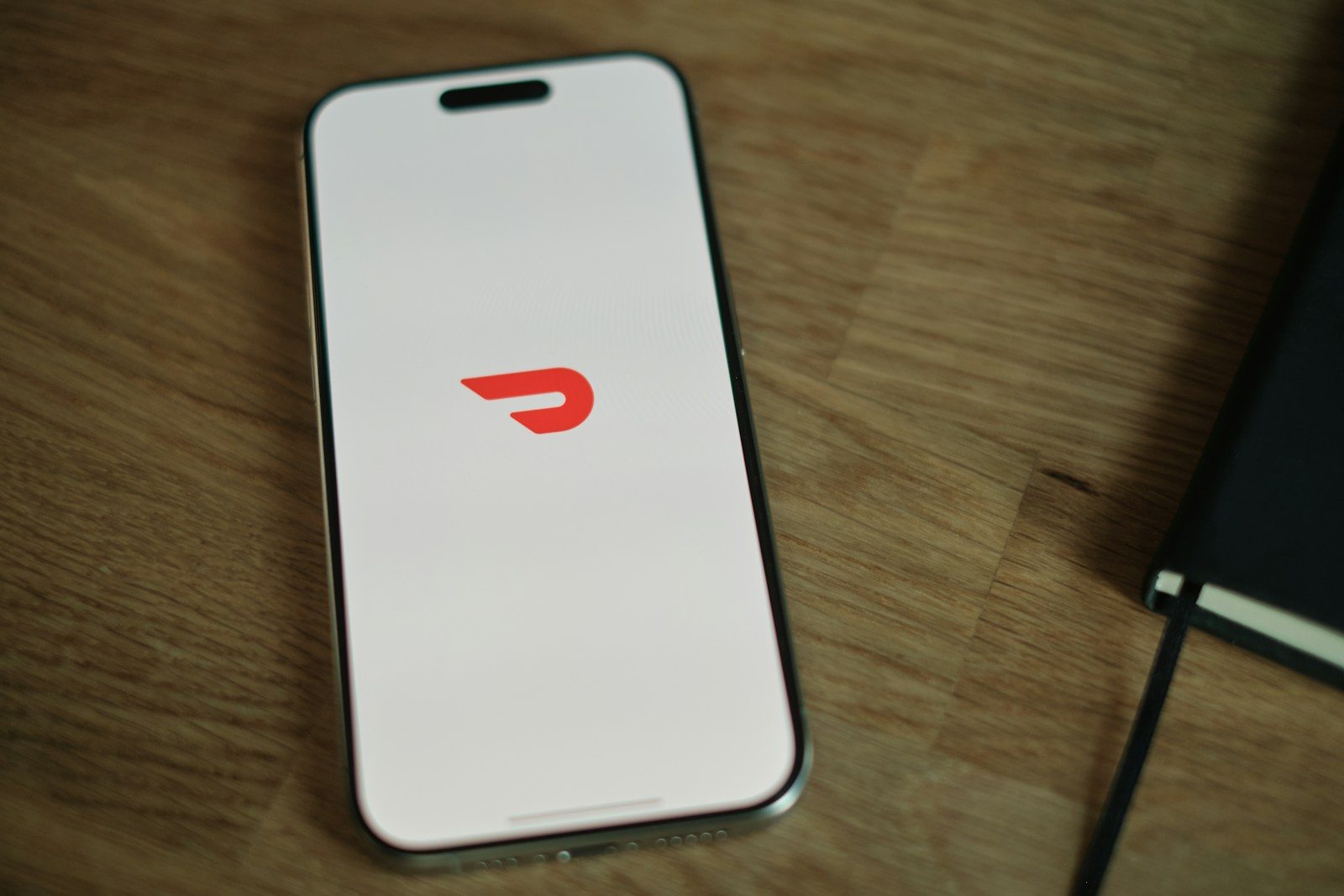 A cell phone sitting on top of a wooden table; DoorDash Tasks