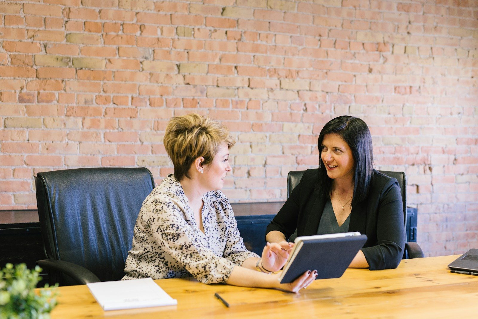 two women sitting on leather chairs in front of table; Every Benefits