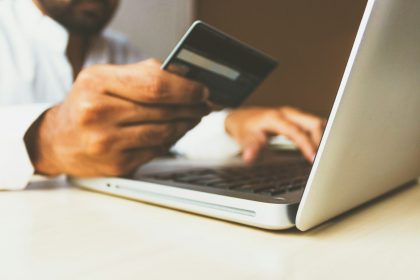 person using laptop computer holding card; small business credit card processing