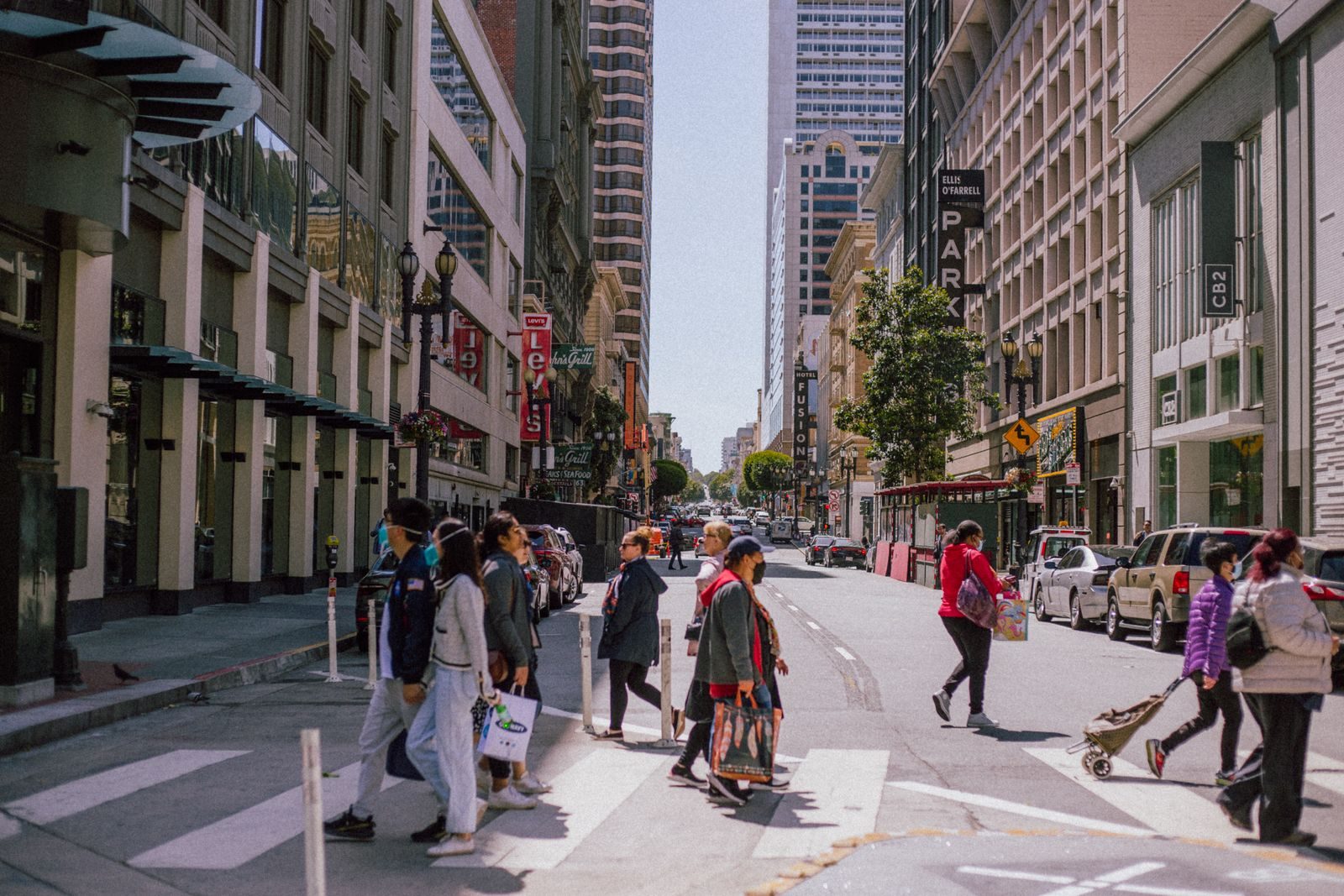 People crossing a city street at a bustling urban intersection during the day, showcasing modern architecture and city life; California gig workers union