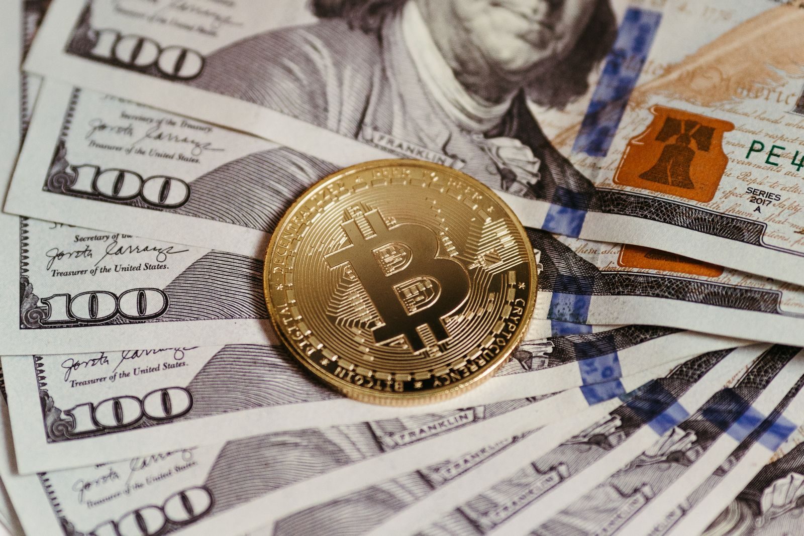 Gold Bitcoin coin resting on US dollar bills showcasing digital and traditional currency; crypto payments small business