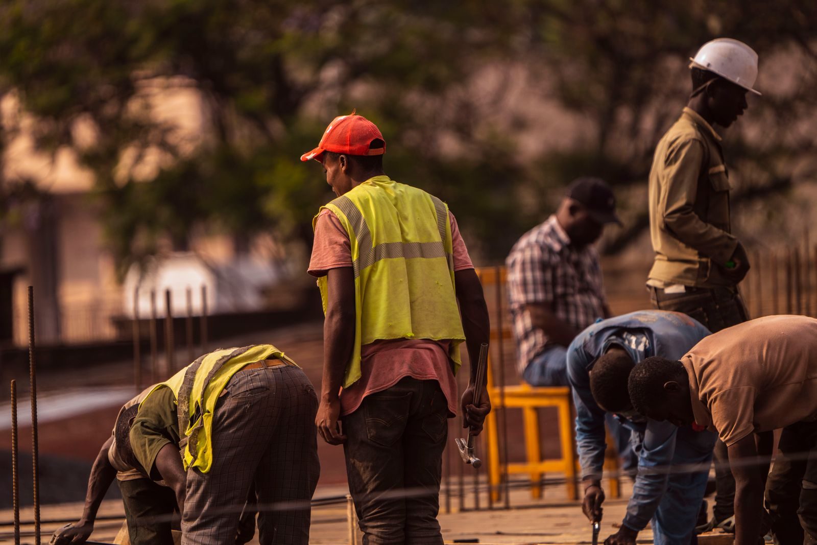 Group of male construction workers on site wearing safety gear during daytime; independent workforce