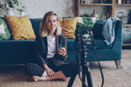 A young woman creating a vlog from her cozy living room with a camera setup; influencer disclosure