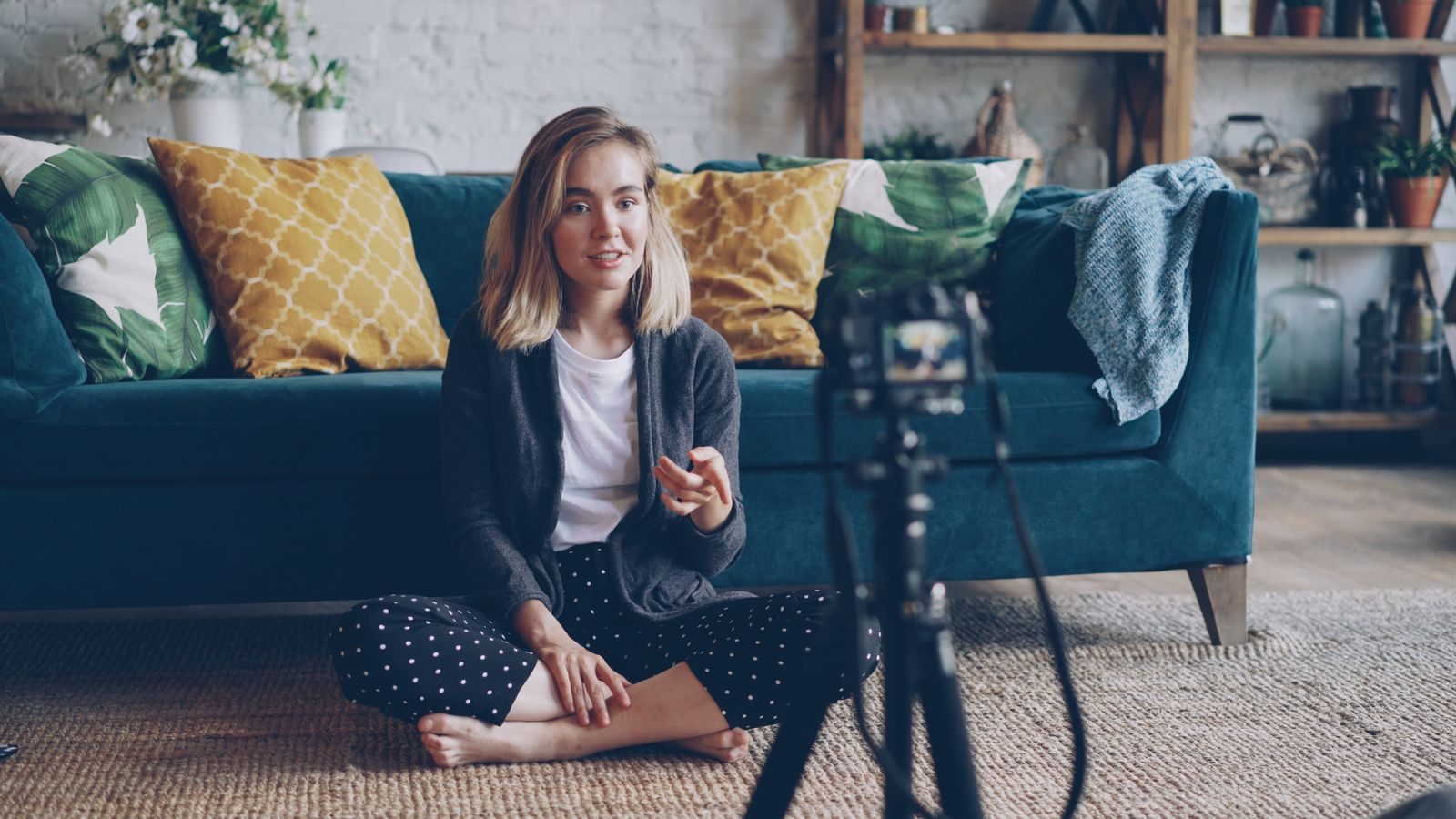 A young woman creating a vlog from her cozy living room with a camera setup; influencer disclosure