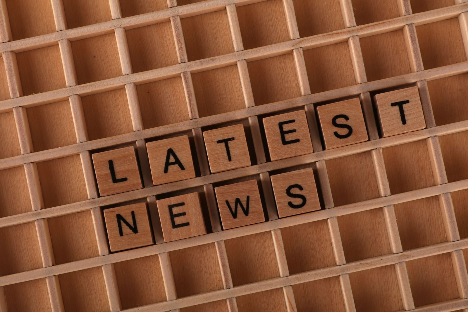 Wooden letter blocks spelling 'Latest News' on a grid surface. Ideal for media concepts; Etsy seller updates 2026