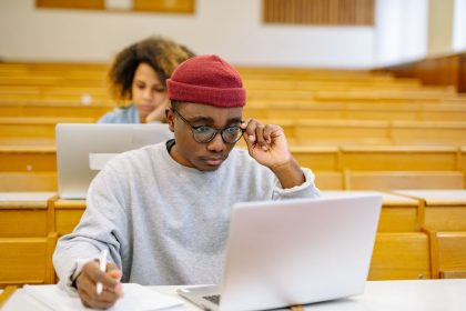 Young adults studying in a university lecture hall with laptops, focused on coursework; HSA eligibility Bronze plans