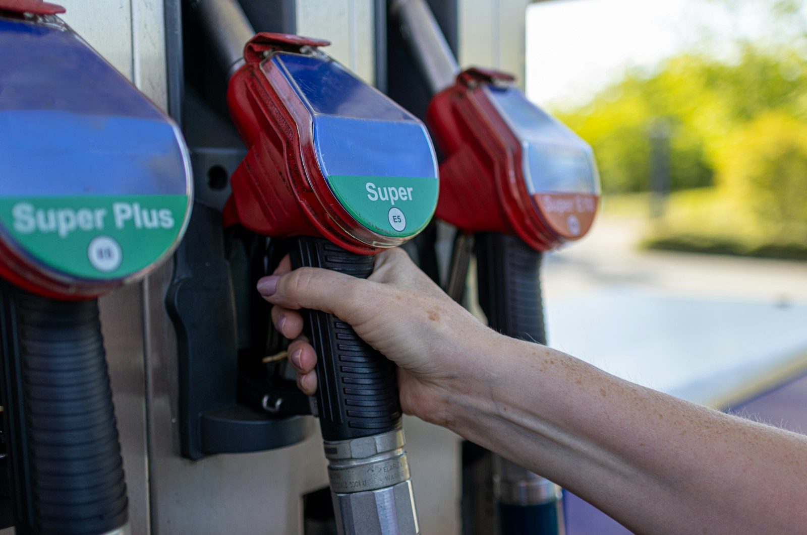a person's hand is holding a gas pump; oil prices self-employed drivers