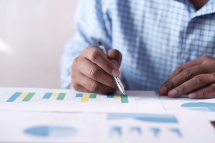 Close-up of hands analyzing colorful graphs, indicating business planning; ADP September jobs report