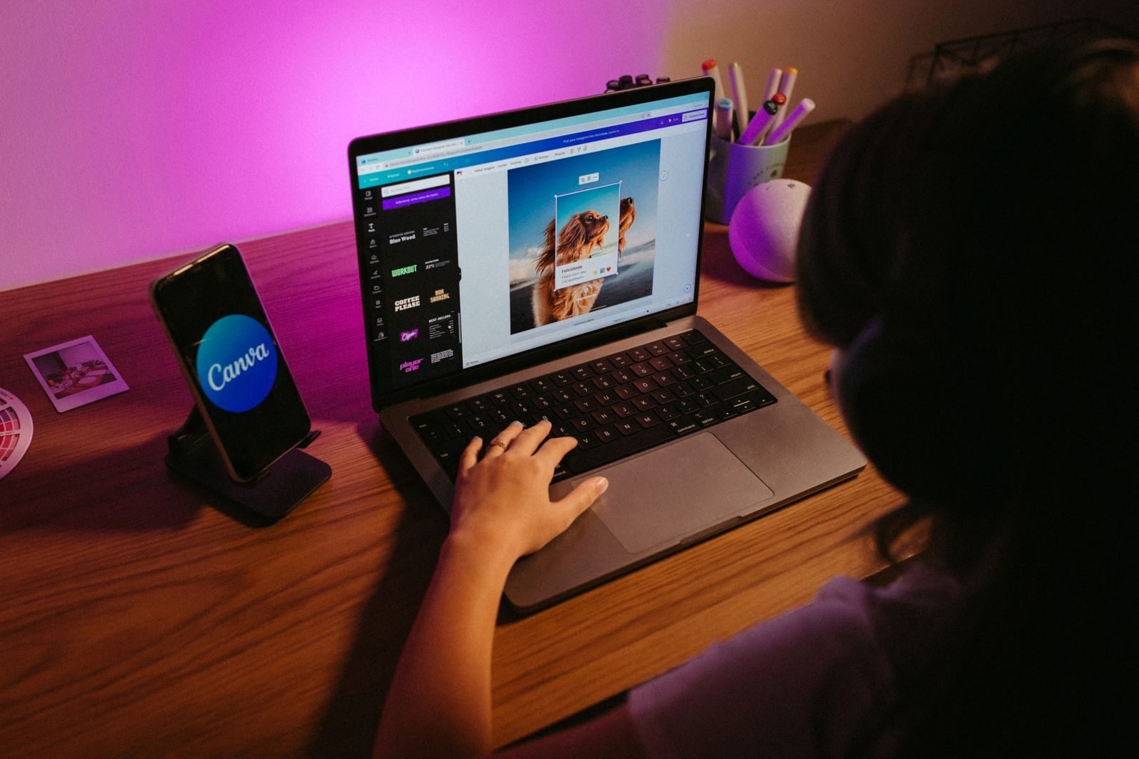Teen working on graphic design using laptop at home with creative tools; Canva ProSuite