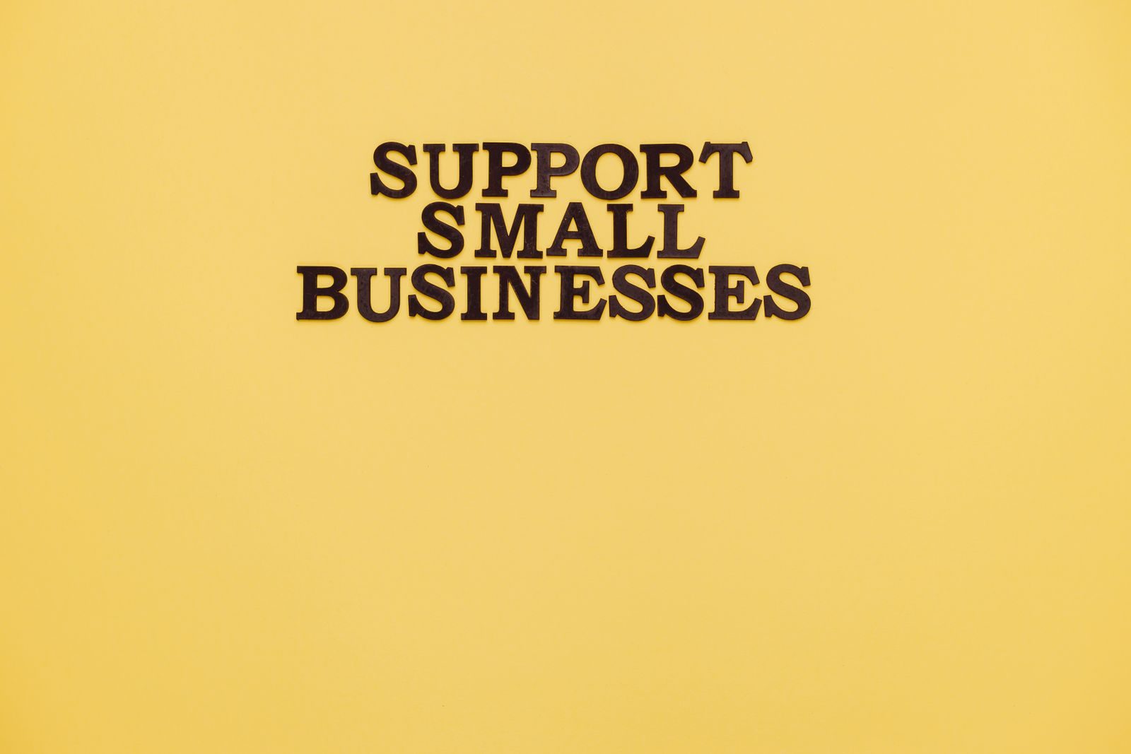 Inspirational image with 'Support Small Businesses' text on a warm yellow background; small business optimism