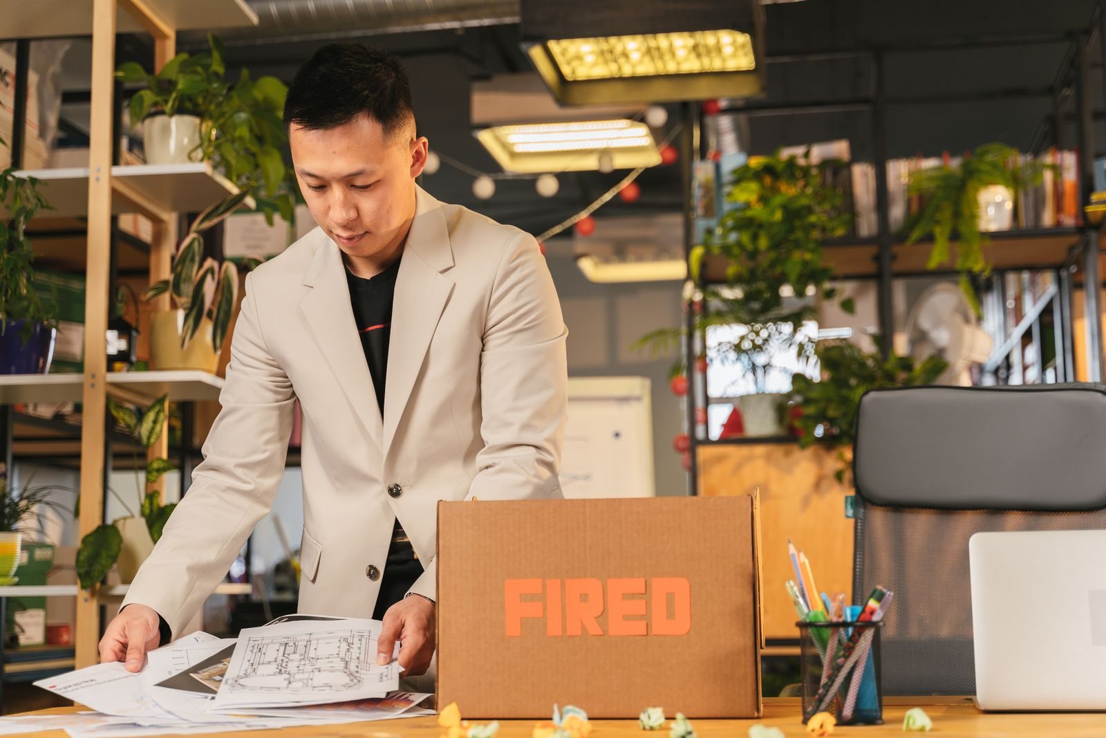 An employee packing documents into a box labeled 'FIRED' in an office environment; HubSpot layoffs