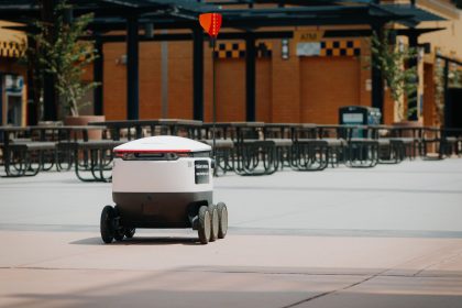 Futuristic delivery robot navigating an empty outdoor plaza, symbolizing modern innovation and mobility; DoorDash AI agent