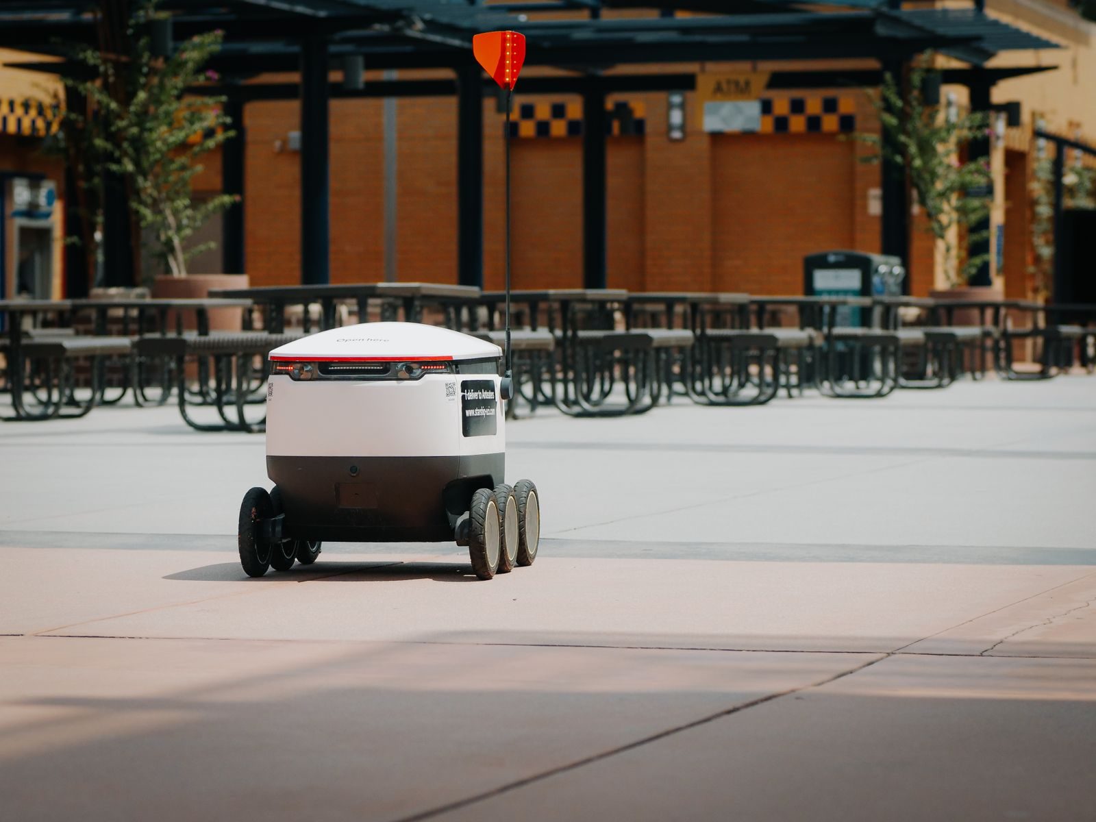 Futuristic delivery robot navigating an empty outdoor plaza, symbolizing modern innovation and mobility; DoorDash AI agent